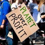 Youth climate protest with participants holding 'Planet Over Profit' sign.