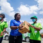 Volunteers work together in an outdoor setting, distributing donation boxes to support their community.